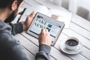 Homem confere notícias em seu Tablet, página exibe fake news. Tecnologia facilita a propagação de Fake News. Homem confere notícias em seu Tablet, página exibe fake news. Tecnologia facilita a propagação de Fake News.